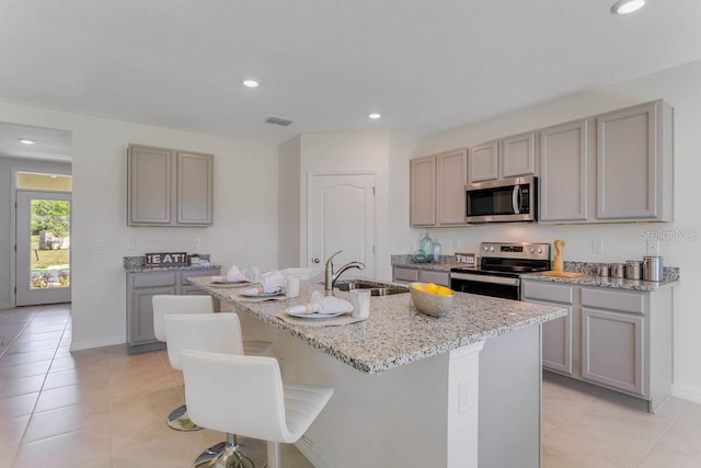 913 Halifax Dr, Kissimmee, FL 34758 - kitchen with stainless steel appliances, gray cabinetry, light tile patterned flooring, an island with sink, and recessed lighting
