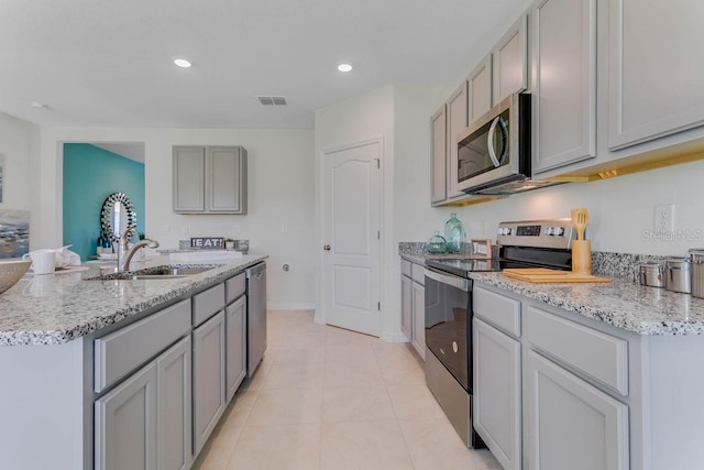 913 Halifax Dr, Kissimmee, FL 34758 - kitchen with appliances with stainless steel finishes, gray cabinetry, light stone counters, light tile patterned flooring, and recessed lighting
