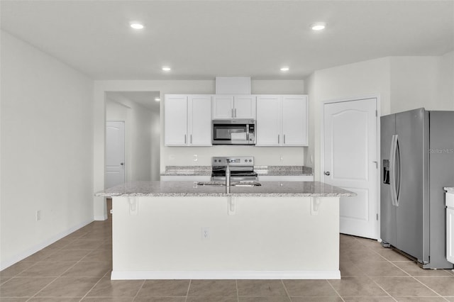 1850 Walnut Creek Dr, Kissimmee, FL 34744 - kitchen with appliances with stainless steel finishes, a kitchen breakfast bar, light stone countertops, white cabinets, and an island with sink