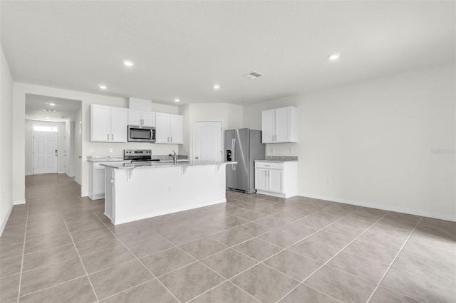 1850 Walnut Creek Dr, Kissimmee, FL 34744 - kitchen featuring appliances with stainless steel finishes, light tile patterned floors, a breakfast bar, white cabinets, and an island with sink