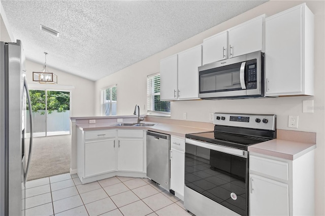 3388 Cypress Point Cir, Saint Cloud, FL 34772 - kitchen featuring stainless steel appliances, a textured ceiling, lofted ceiling, light tile patterned flooring, and white cabinets