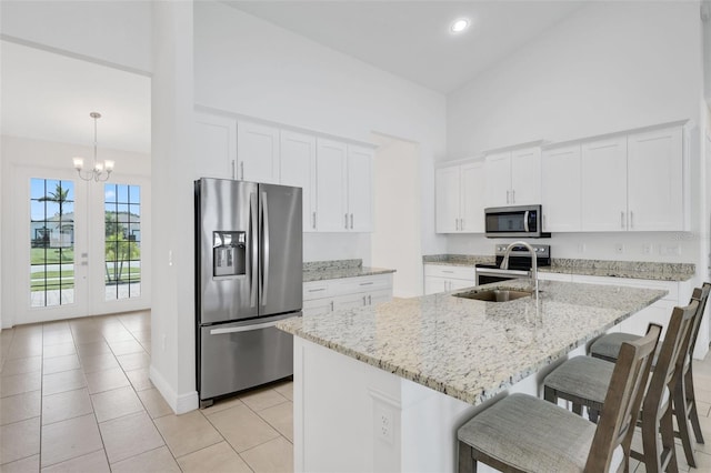 2912 SW Savona Blvd, Port St Lucie, FL 34953 - kitchen with stainless steel appliances, a high ceiling, a kitchen bar, light tile patterned flooring, and a chandelier