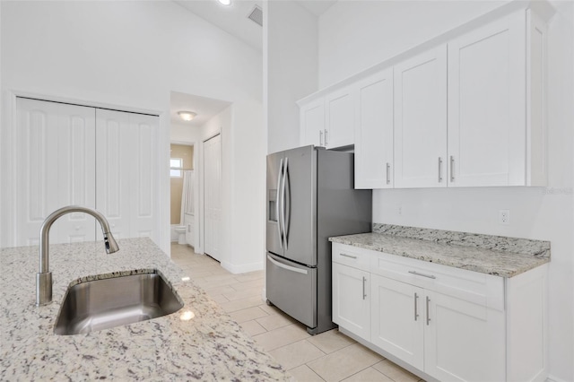 2912 SW Savona Blvd, Port St Lucie, FL 34953 - kitchen with stainless steel fridge with ice dispenser, white cabinetry, light stone counters, a towering ceiling, and light tile patterned floors