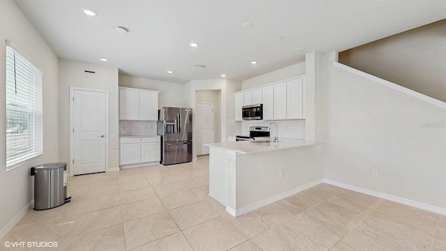 4501 Sparkling Shell Ave, Kissimmee, FL 34746 - kitchen with stainless steel appliances, a peninsula, white cabinetry, light countertops, and decorative backsplash
