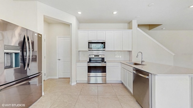 4501 Sparkling Shell Ave, Kissimmee, FL 34746 - kitchen featuring appliances with stainless steel finishes, decorative backsplash, light countertops, a peninsula, and white cabinets