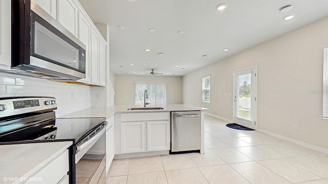 4501 Sparkling Shell Ave, Kissimmee, FL 34746 - kitchen with appliances with stainless steel finishes, a peninsula, decorative backsplash, white cabinets, and light countertops