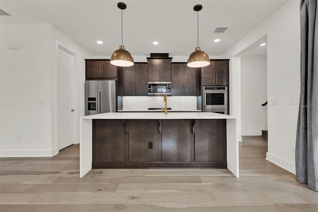 7412 Estuary Lake Loop, Celebration, FL 34747 - kitchen featuring stainless steel appliances, light countertops, light wood finished floors, dark brown cabinets, and recessed lighting