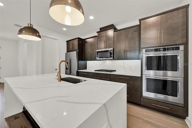 7412 Estuary Lake Loop, Celebration, FL 34747 - kitchen with stainless steel appliances, a center island with sink, light wood-style floors, recessed lighting, and dark brown cabinetry