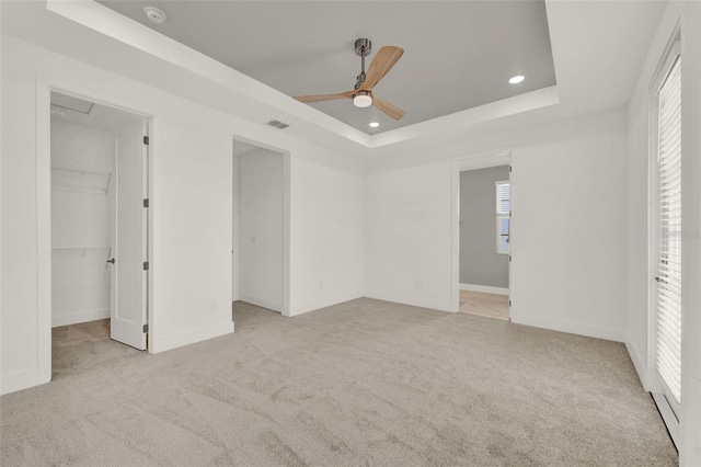7412 Estuary Lake Loop, Celebration, FL 34747 - unfurnished bedroom featuring carpet, a tray ceiling, a walk in closet, recessed lighting, and multiple windows