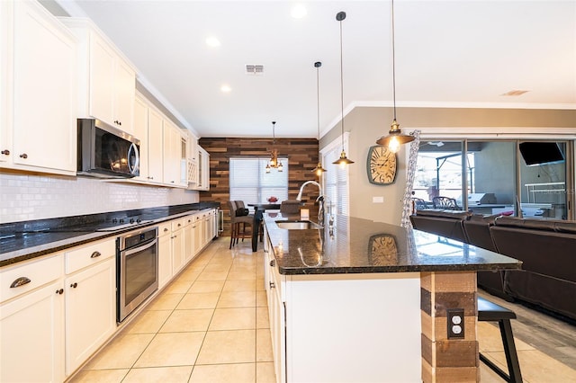 9379 Royal Estates Blvd, Orlando, FL 32836 - kitchen featuring stainless steel appliances, open floor plan, a center island with sink, a kitchen bar, and wood walls