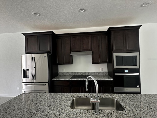 14099 Lochend Way, Winter Garden, FL 34787 - kitchen featuring black appliances, under cabinet range hood, dark stone counters, dark brown cabinetry, and a textured ceiling
