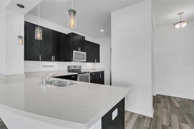 17458 Chateau Pine Way, Clermont, FL 34711 - kitchen featuring stainless steel appliances, dark cabinetry, wood finished floors, light countertops, and hanging light fixtures