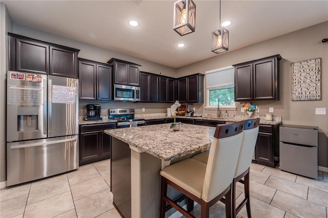 4024 Blazewater Ct, Eustis, FL 32736 - kitchen with appliances with stainless steel finishes, light tile patterned floors, a center island, light stone countertops, and recessed lighting