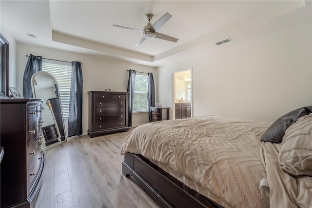 4024 Blazewater Ct, Eustis, FL 32736 - bedroom featuring a raised ceiling, light wood-style floors, ceiling fan, and ensuite bath