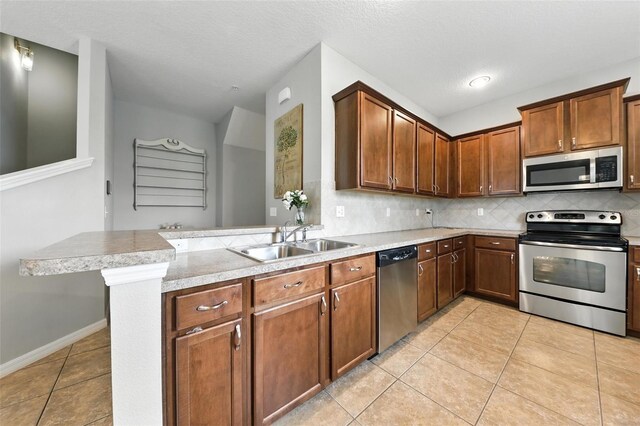 1551 Scarlet Oak Loop Unit B, Winter Garden, FL 34787 - kitchen with appliances with stainless steel finishes, light tile patterned flooring, a peninsula, decorative backsplash, and light countertops