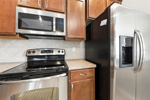 1551 Scarlet Oak Loop Unit B, Winter Garden, FL 34787 - kitchen featuring appliances with stainless steel finishes, light countertops, tasteful backsplash, and brown cabinets