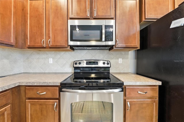 1551 Scarlet Oak Loop Unit B, Winter Garden, FL 34787 - kitchen featuring stainless steel appliances, light countertops, tasteful backsplash, and brown cabinets