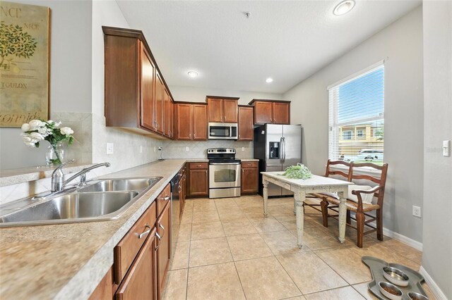 1551 Scarlet Oak Loop Unit B, Winter Garden, FL 34787 - kitchen featuring stainless steel appliances, backsplash, light countertops, light tile patterned flooring, and brown cabinets