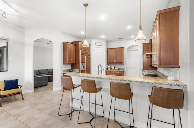 32619 View Haven Ln, Sorrento, FL 32776 - kitchen featuring arched walkways, a peninsula, decorative backsplash, brown cabinets, and recessed lighting