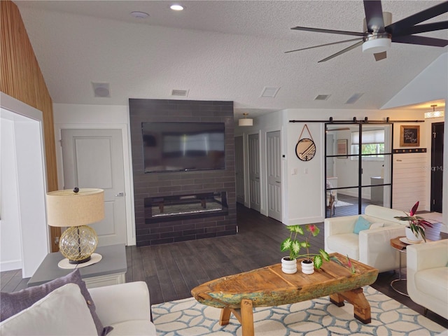 142 Reef Rd, South Daytona, FL 32119 - living room with wood finished floors, vaulted ceiling, a ceiling fan, a barn door, and a textured ceiling