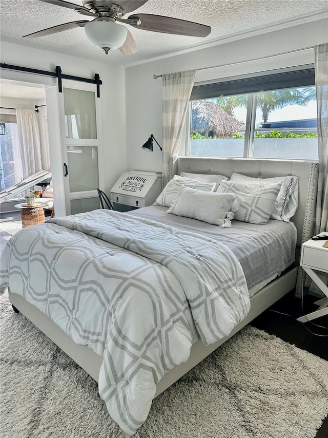 142 Reef Rd, South Daytona, FL 32119 - bedroom featuring multiple windows, a barn door, a textured ceiling, ceiling fan, and wood finished floors