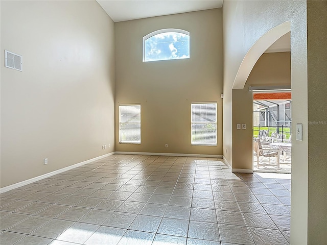 132 Cordova Ave, Davenport, FL 33897 - empty room featuring arched walkways, light tile patterned flooring, and a towering ceiling
