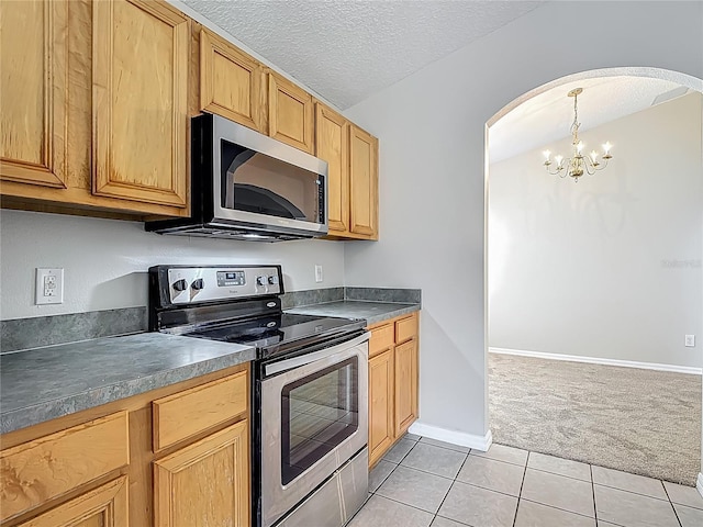 132 Cordova Ave, Davenport, FL 33897 - kitchen featuring appliances with stainless steel finishes, light carpet, arched walkways, a chandelier, and light tile patterned floors
