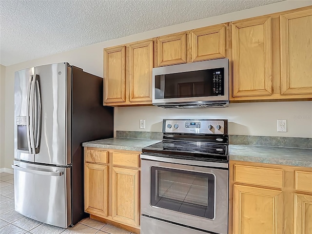 132 Cordova Ave, Davenport, FL 33897 - kitchen with appliances with stainless steel finishes, light tile patterned floors, light brown cabinets, and a textured ceiling