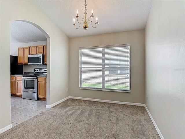 132 Cordova Ave, Davenport, FL 33897 - kitchen featuring appliances with stainless steel finishes, a textured ceiling, light colored carpet, arched walkways, and a chandelier