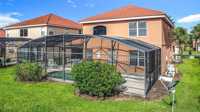 132 Cordova Ave, Davenport, FL 33897 - back of property featuring a patio, a lawn, glass enclosure, a tiled roof, and stucco siding