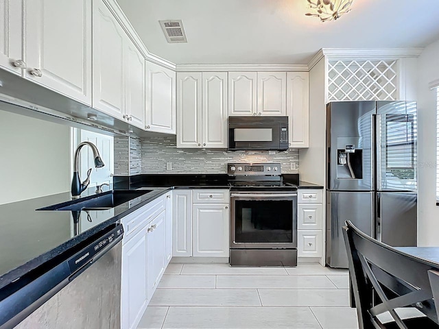 6140 Burnside Cir Unit 204, Orlando, FL 32822 - kitchen featuring appliances with stainless steel finishes, dark countertops, decorative backsplash, white cabinetry, and light tile patterned floors