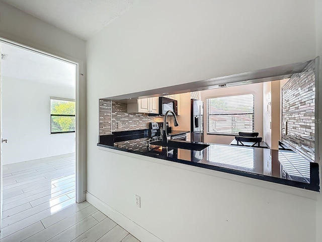 6140 Burnside Cir Unit 204, Orlando, FL 32822 - kitchen featuring stainless steel fridge with ice dispenser, black microwave, dark countertops, backsplash, and healthy amount of natural light