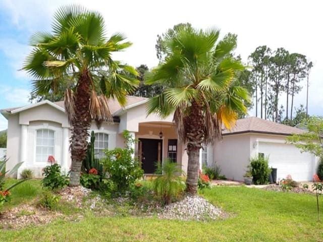 8 Barkley Ln, Palm Coast, FL 32137 - view of front of house with an attached garage, stucco siding, and a front lawn