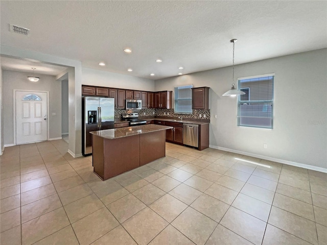 2587 Isabela Ter, Kissimmee, FL 34743 - kitchen featuring stainless steel appliances, tasteful backsplash, light tile patterned floors, a center island, and dark brown cabinets