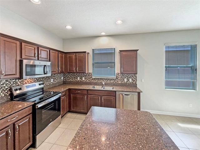 2587 Isabela Ter, Kissimmee, FL 34743 - kitchen featuring stainless steel appliances, light tile patterned flooring, backsplash, dark stone countertops, and dark brown cabinets