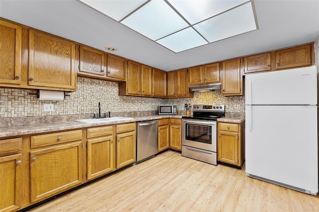 1384 La Paloma Cir, Winter Springs, FL 32708 - kitchen with appliances with stainless steel finishes, under cabinet range hood, brown cabinets, tasteful backsplash, and light wood-style floors