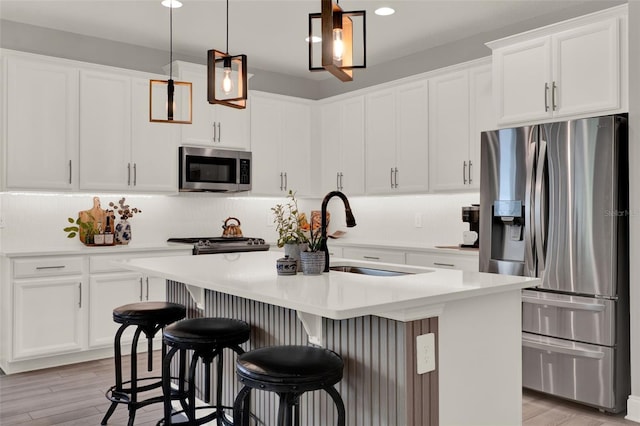 1219 Foltz Loop, Oakland, FL 34787 - kitchen with stainless steel appliances, a kitchen island with sink, white cabinetry, light countertops, and recessed lighting