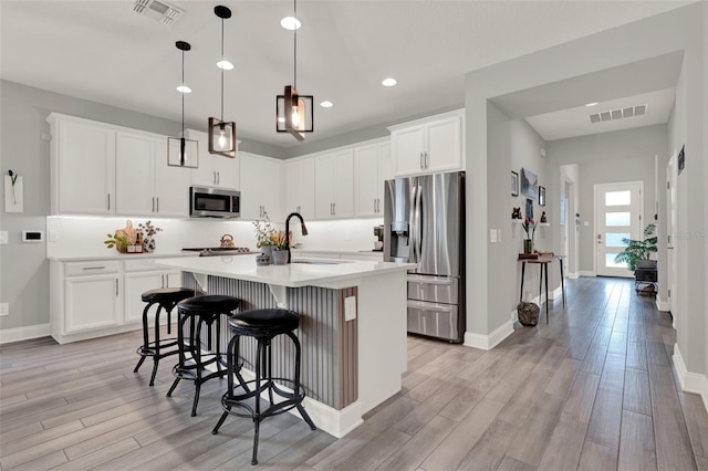 1219 Foltz Loop, Oakland, FL 34787 - kitchen featuring stainless steel appliances, light wood-style floors, recessed lighting, a breakfast bar, and light countertops