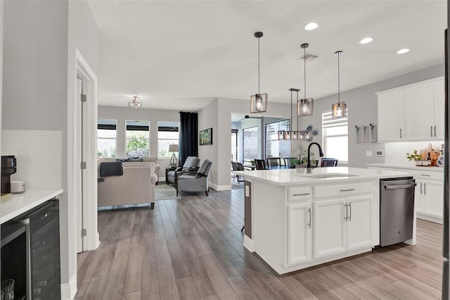 1219 Foltz Loop, Oakland, FL 34787 - kitchen featuring stainless steel dishwasher, light wood finished floors, light countertops, beverage cooler, and recessed lighting