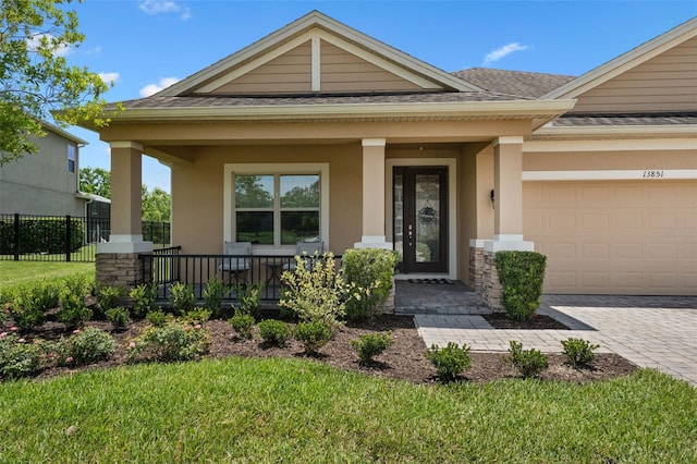 13851 Jomatt Loop, Winter Garden, FL 34787 - property entrance with covered porch, stucco siding, a shingled roof, driveway, and a garage