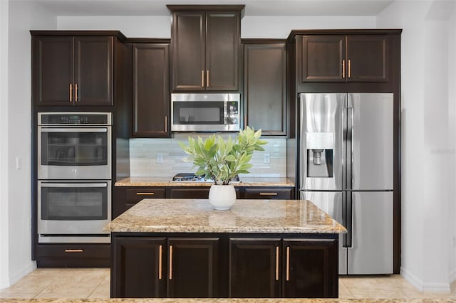 13851 Jomatt Loop, Winter Garden, FL 34787 - kitchen with stainless steel appliances, decorative backsplash, light stone countertops, dark brown cabinetry, and light tile patterned floors