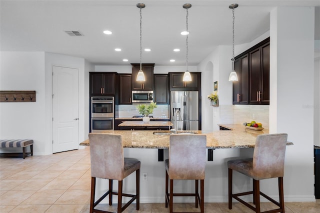 13851 Jomatt Loop, Winter Garden, FL 34787 - kitchen featuring appliances with stainless steel finishes, a peninsula, tasteful backsplash, light stone counters, and recessed lighting