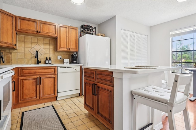 364 Northpointe Ct Unit 208, Altamonte Springs, FL 32701 - kitchen featuring white appliances, decorative backsplash, light countertops, a textured ceiling, and brown cabinets