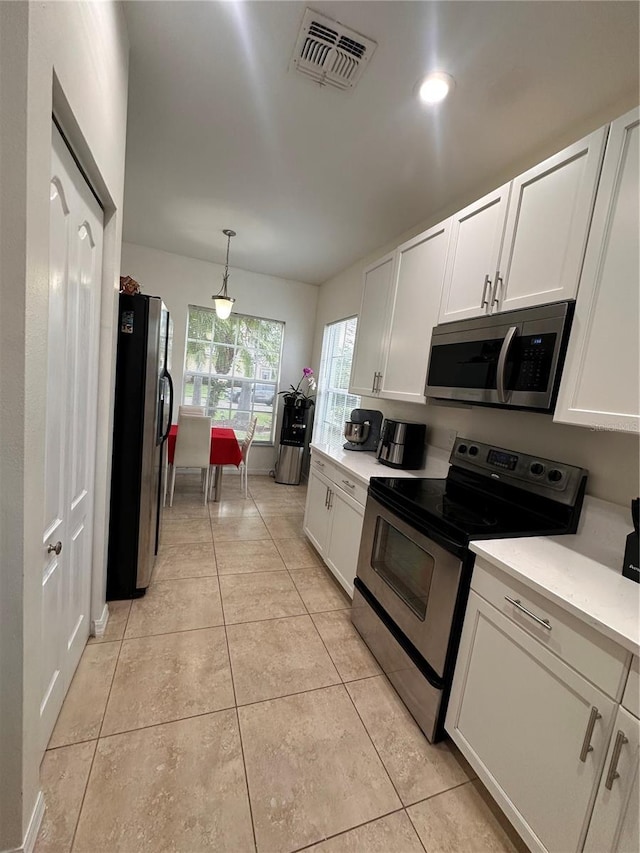 10110 SW Chadwick Dr, Port St Lucie, FL 34987 - kitchen featuring stainless steel appliances, light countertops, white cabinets, and light tile patterned floors