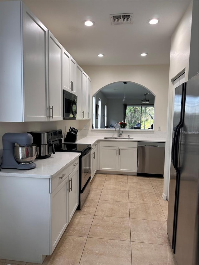 10110 SW Chadwick Dr, Port St Lucie, FL 34987 - kitchen featuring black appliances, arched walkways, light countertops, recessed lighting, and light tile patterned floors