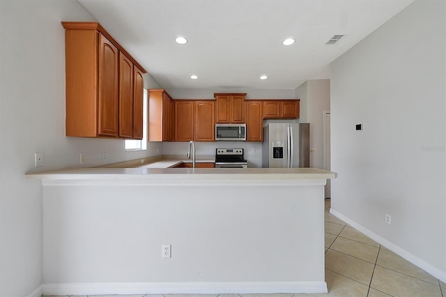 9049 Edenshire Cir, Orlando, FL 32836 - kitchen with stainless steel appliances, a peninsula, light countertops, light tile patterned floors, and recessed lighting