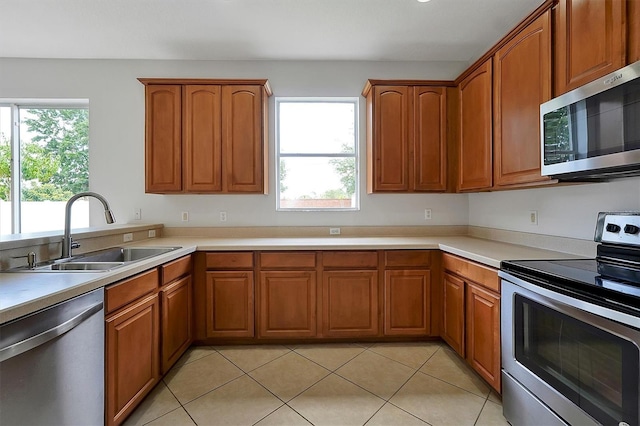 9049 Edenshire Cir, Orlando, FL 32836 - kitchen with appliances with stainless steel finishes, brown cabinetry, light countertops, and light tile patterned floors