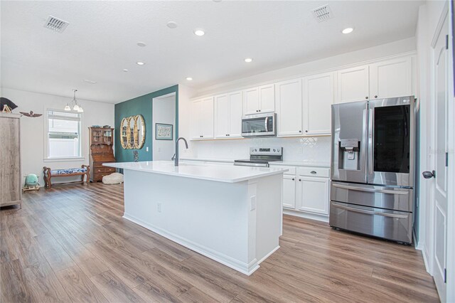 786 Steerview St, Saint Cloud, FL 34771 - kitchen with appliances with stainless steel finishes, white cabinetry, wood finished floors, a center island with sink, and light countertops