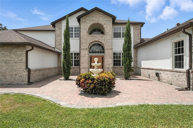 15350 Arabian Way, Montverde, FL 34756 - french country inspired facade featuring brick siding, stucco siding, a patio area, and roof with shingles