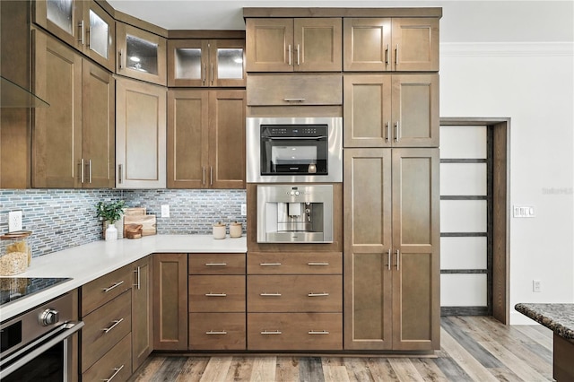 15350 Arabian Way, Montverde, FL 34756 - kitchen featuring oven, ornamental molding, backsplash, light wood-style floors, and glass insert cabinets